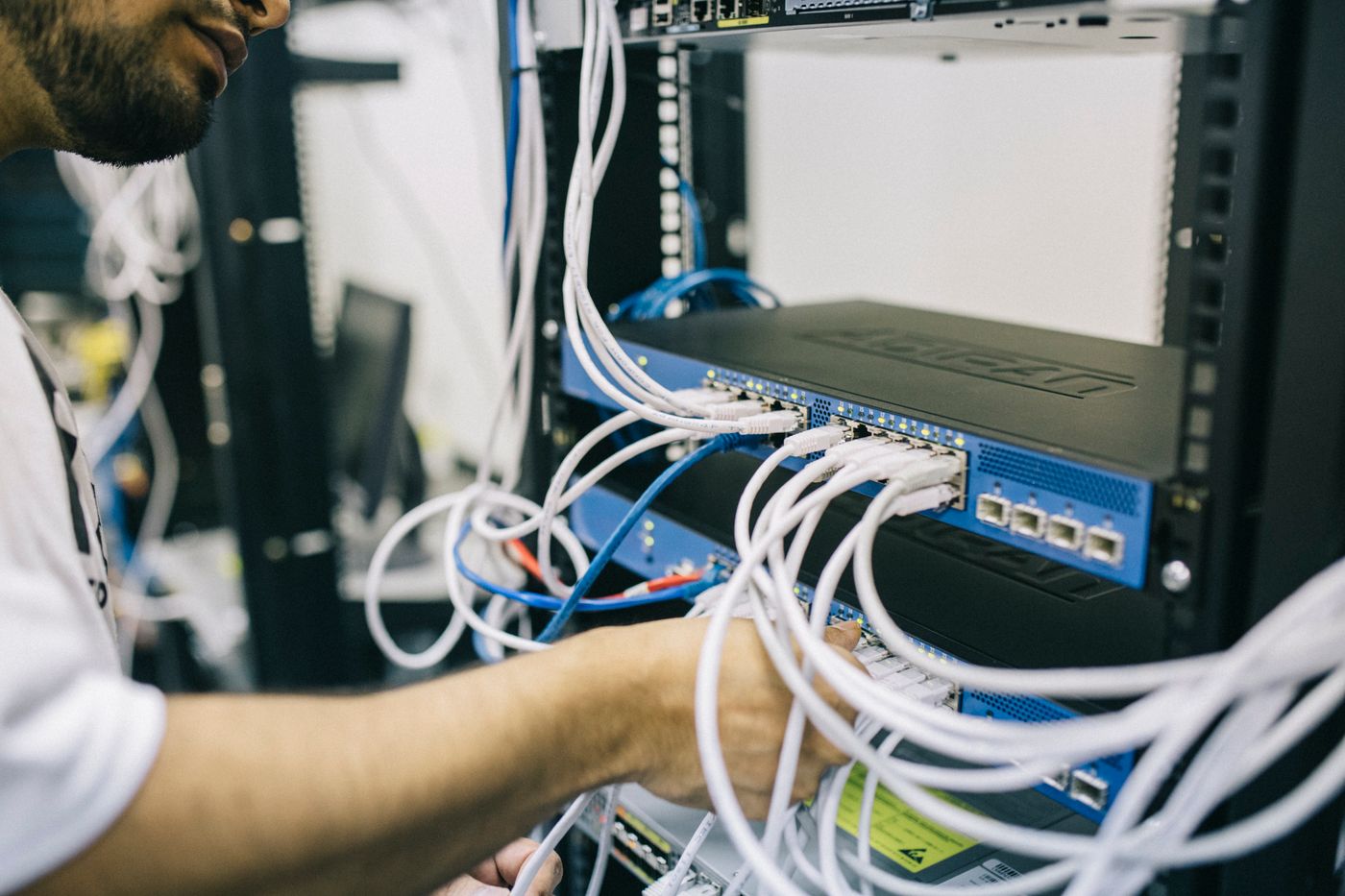 Hands patching network cables into a switch in an equipment rack