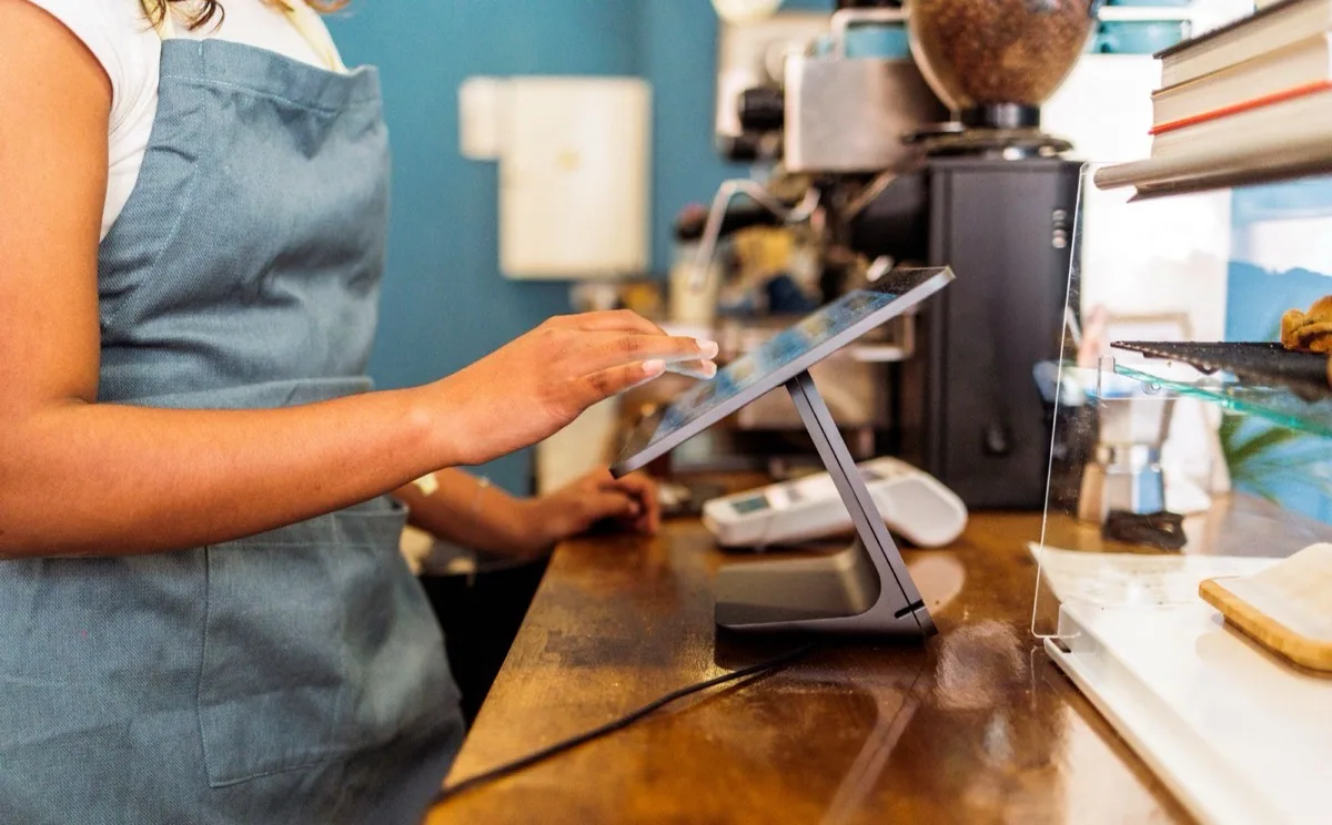 A cafe counter with a point of sale tablet and a card reader in use